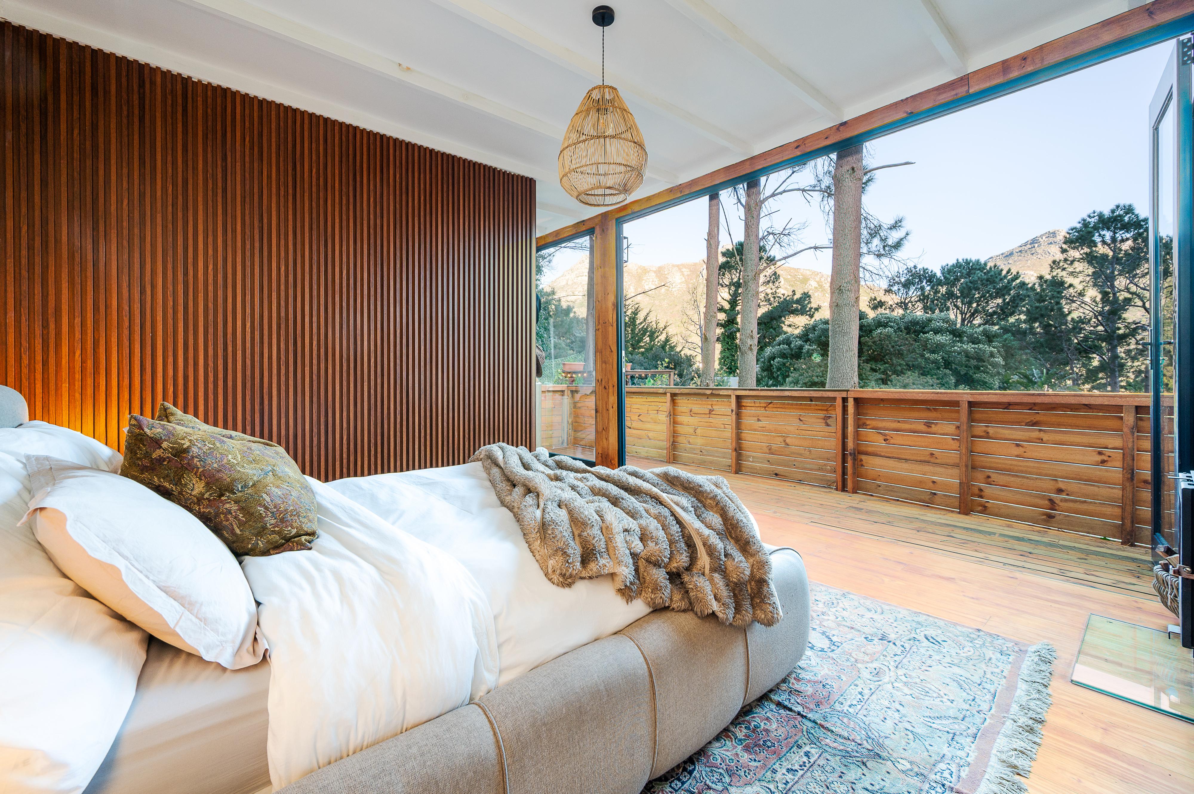 Bedroom with a vertical timber slat wall opening onto a deck with mountain views