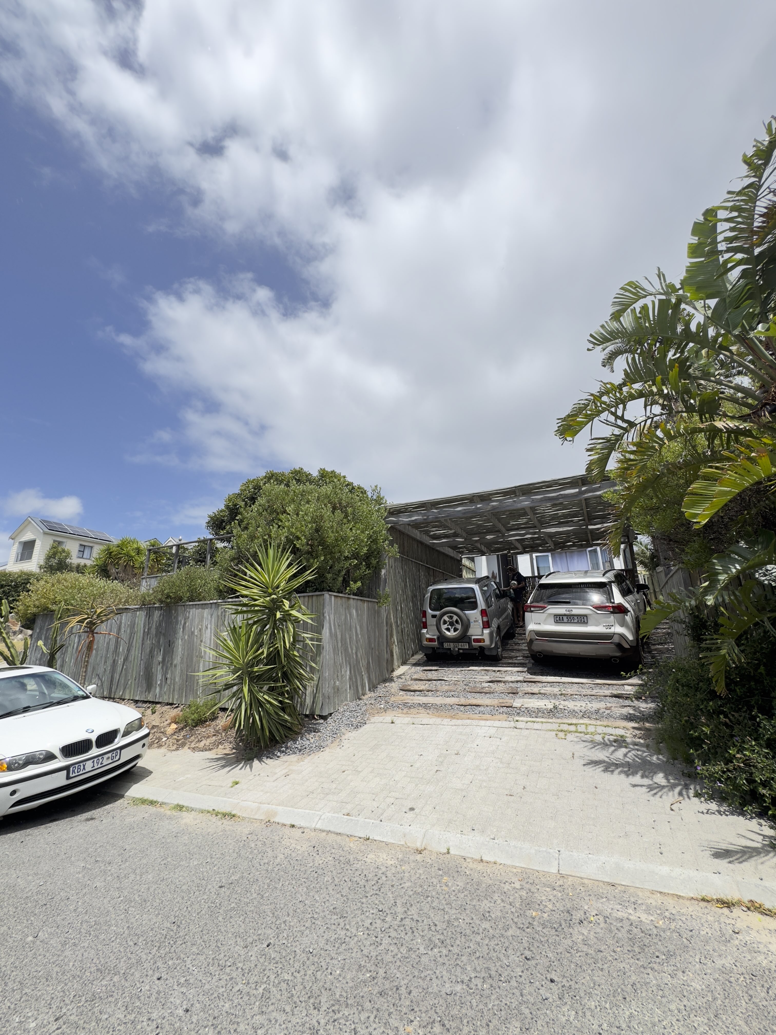 The new driveway and carport pergola with timber fencing and palms out front