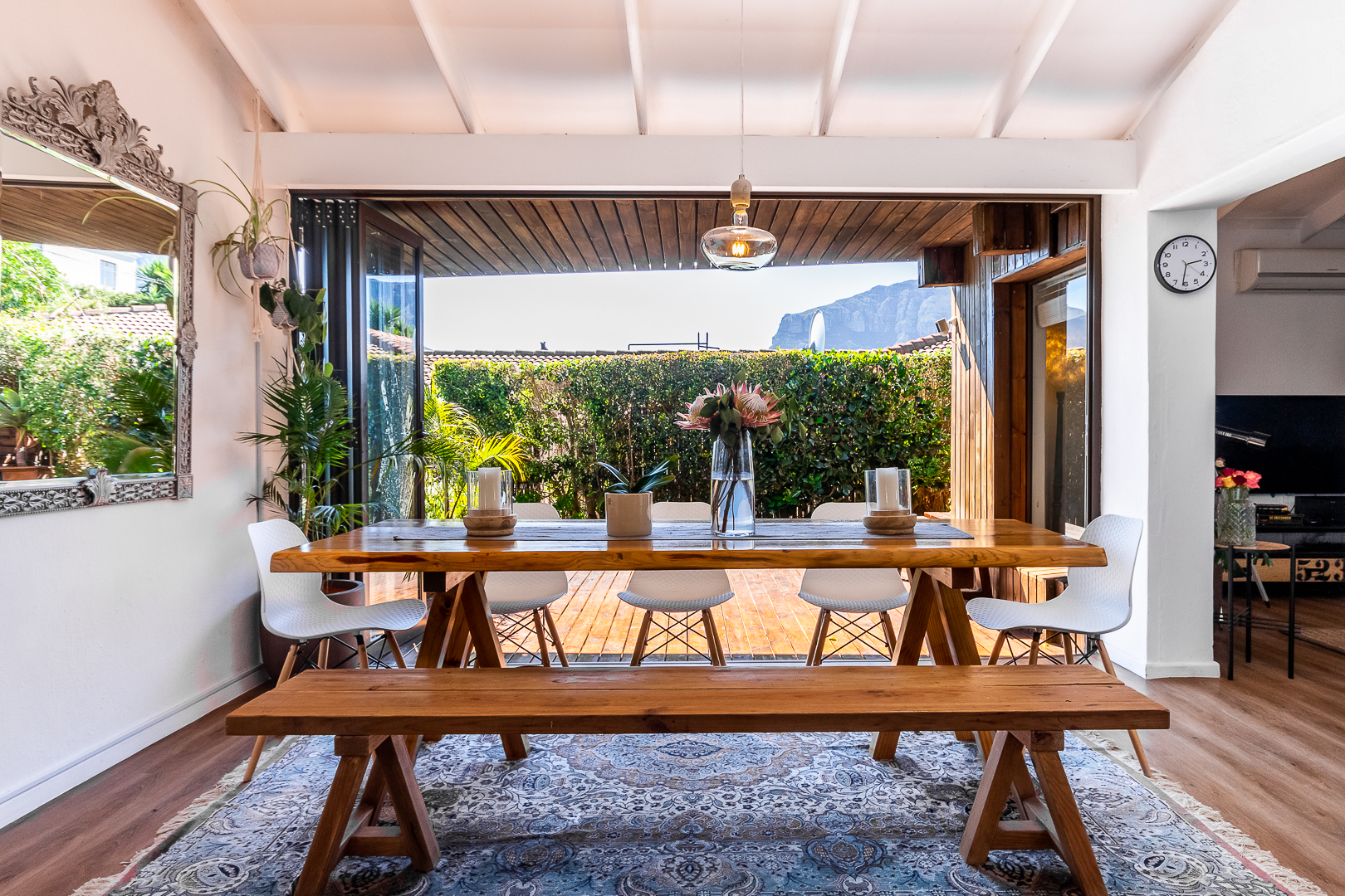 Dining area with a live edge timber table and folding glass doors open to the deck and mountains