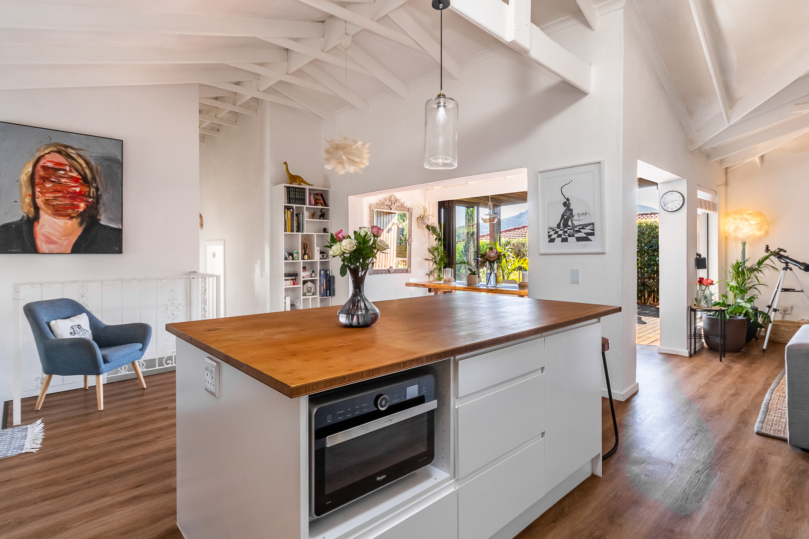 Bright renovated kitchen with a wood topped island beneath a white vaulted beamed ceiling