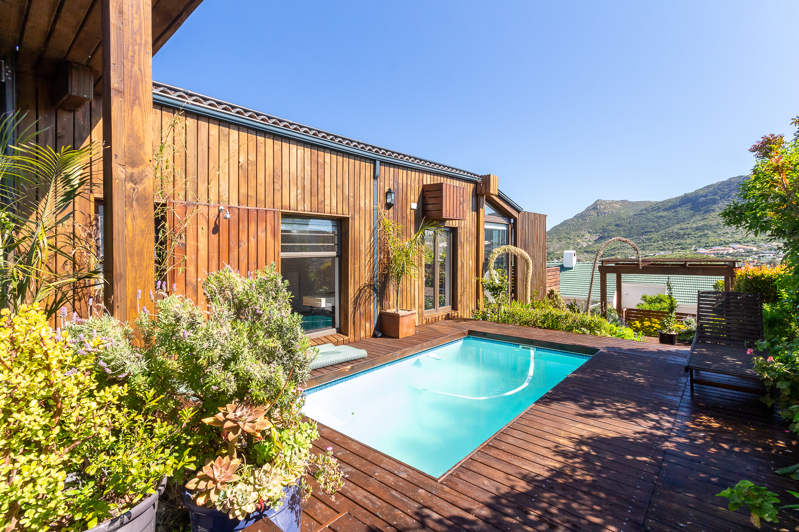 Timber clad exterior with a plunge pool set into the deck and mountains beyond